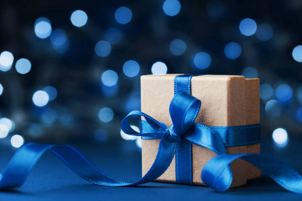 pudełko na prezenty świąteczne lub prezent z kokardką na niebieskim tle bokeh. magiczna kartka z życzeniami świątecznymi. - gift blue christmas religious celebration zdjęcia i obrazy z banku zdjęć