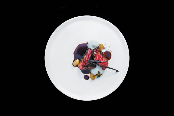 istock Poorly-done piece of meat on a plate isolated on a black background. 857337516