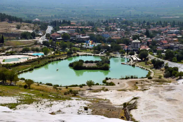 Photo of A mineral lake on the background of the village and white mineral deposits.