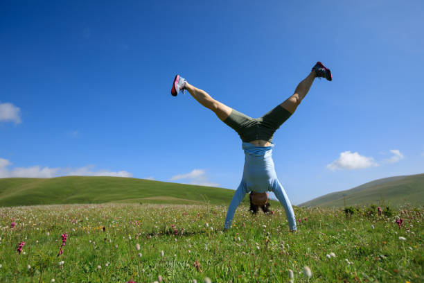 istock woman doing a handstand in a mountain peak meadow 857345648
