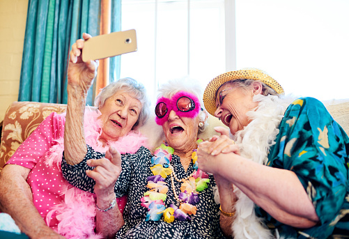 Shot of a group carefree elderly people wearing funky costumes and getting close for a selfie inside of a building