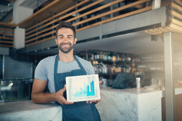 Investing your passion pays off Portrait of a young man holding a digital tablet with a graph on the screen at a coffee shop franchising photos stock pictures, royalty-free photos & images