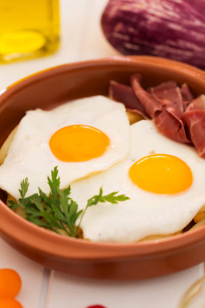 istock Fried eggs in a ceramic cup with spanish jamon for breakfast on a white background. Close up 857365644