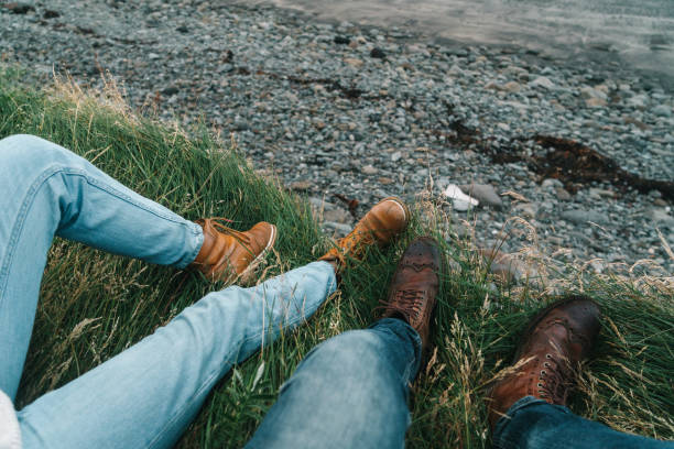 Close up of couple's legs in leather shoes on the black sand beach