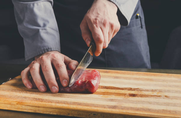 istock Chef cutting filet mignon on wooden board at restaurant kitchen 857375738