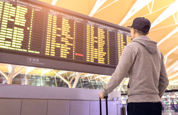 istock Passenger looking at flights information board in airport terminal 857376094