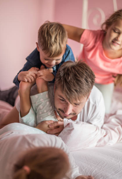 istock Father playing in bed with his son and daughter 857403842