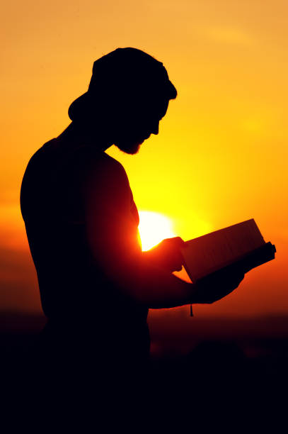 istock Silhoette of relaxed man reading a book at sunset 857404446