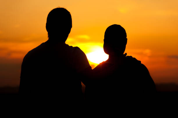 Two male friends or homosexual couple enjoying sunset time together. Relaxation and leisure concept.