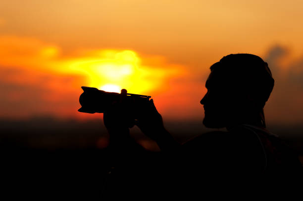 istock Silhouette of young man with camera at sunset time 857407250