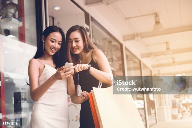 Two Asian Woman Standing At Store Front With Happy Watching Smart Phone At Shopping Mall Center Stock Photo - Download Image Now