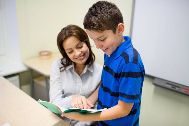 istock school boy with notebook and teacher in classroom 857418600