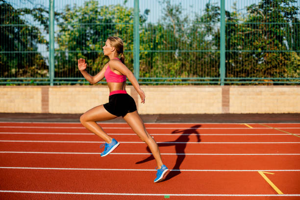 istock Side view beautiful young woman exercise jogging and running on athletic track on stadium 857425962