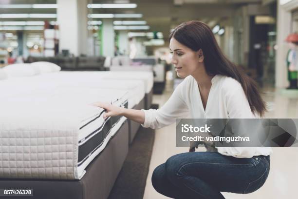 Photo libre de droit de Une Femme Choisit Un Matelas Dans Un Magasin Elle Sassoit À Côté De Lui Et Lui Examine banque d'images et plus d'images libres de droit de Matelas