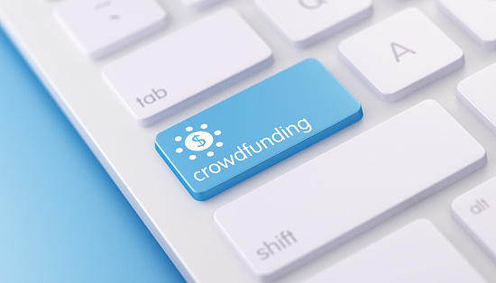 High quality 3d render of a modern keyboard with crowdfunding button on a blue background and copy space. Crowdfunding keyboard button has a text and an icon on it. Crowdfunding keyboard button is in focus. Horizontal composition with copy space.