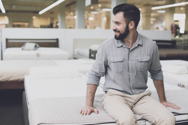istock A man in a large store chooses a mattress for himself. He sat down on him to try it out 857430496