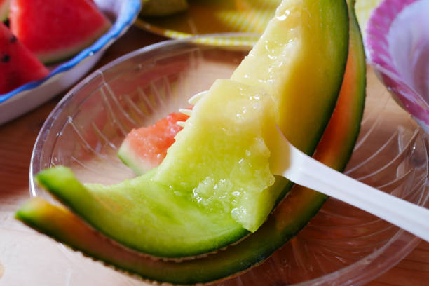 Close up spoon scoop dip on fresh sliced green melon with plate at melon farm in Furano, Hokkaido, Japan. Close up spoon scoop dip on fresh sliced green melon with plate at melon farm in Furano, Hokkaido, Japan. Juicy summer sweet fruit. yellow melons field stock pictures, royalty-free photos & images