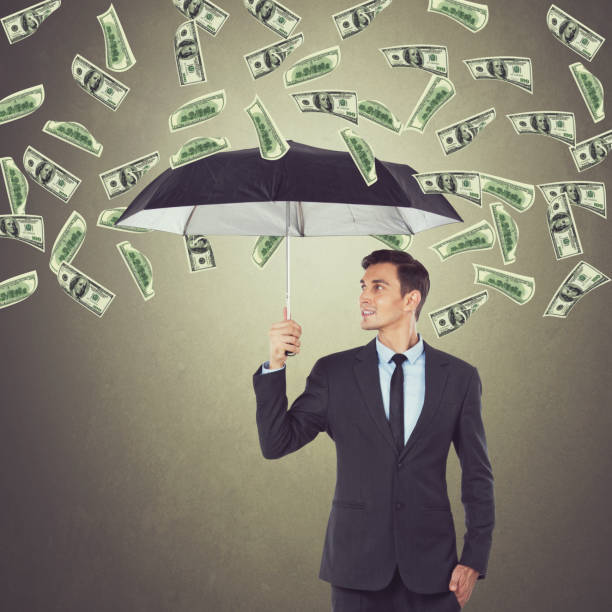 istock Businessman with umbrella and raining dollar bills 857438112