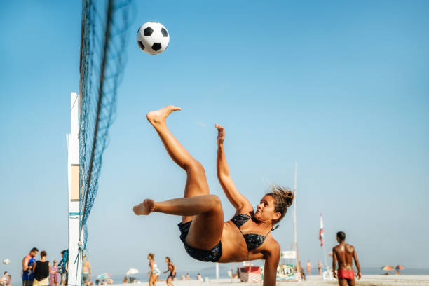 brazilian woman jumping and kicking ball on beach in brazil - beach football imagens e fotografias de stock