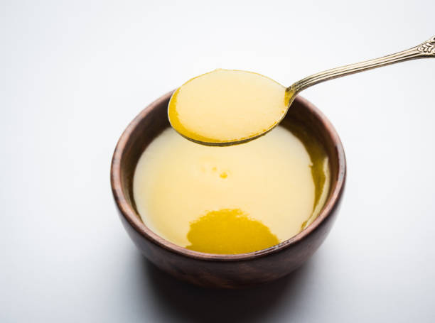 Ghee or clarified butter close up in wooden bowl and silver spoon, selective focus Ghee or clarified butter close up in wooden bowl and silver spoon, selective focus Apply ghee on face stock pictures, royalty-free photos & images