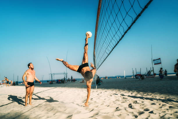 uomo brasiliano che salta e calcia palla sulla spiaggia in brasile - volleyball net leisure activity beach foto e immagini stock