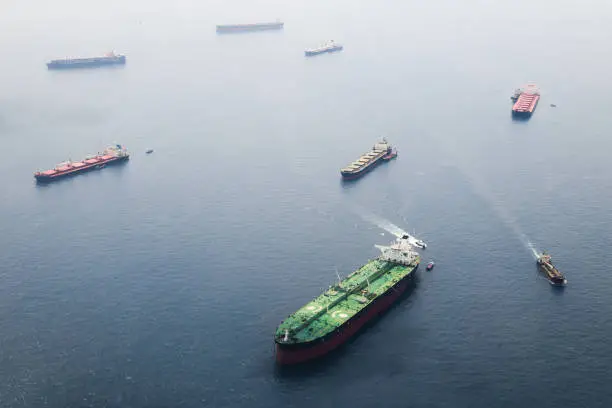 Ships in Straits of Singapore from the height. Big tanker with two helicopter platforms stay on anchor and wait for their turn to enter the port for unloading or loading