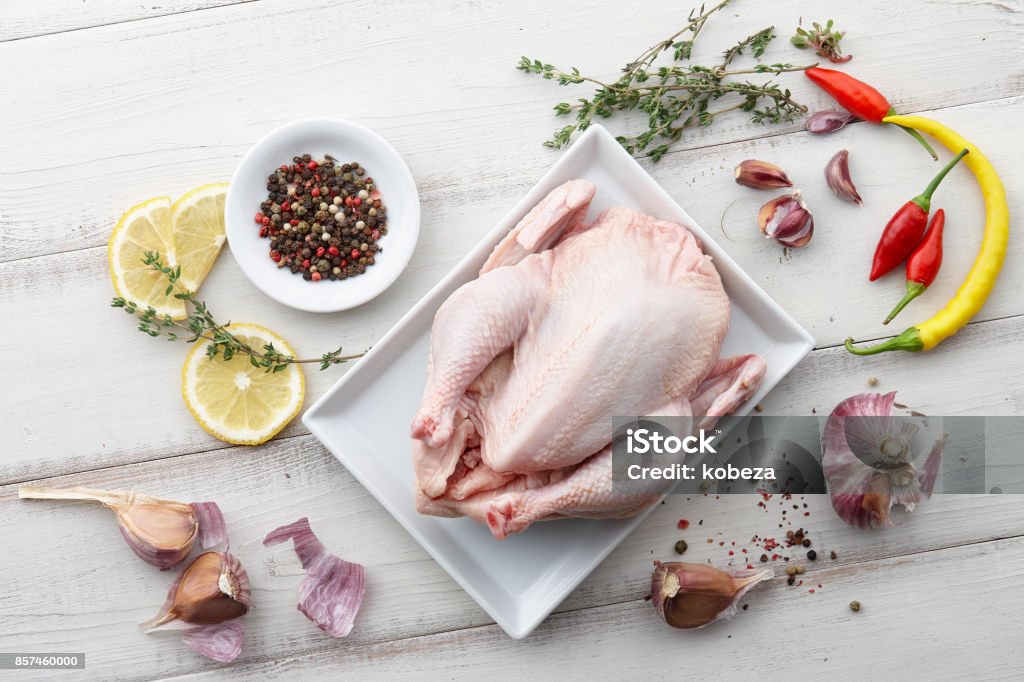 Pollo crudo, erbe aromatiche e spezie su sfondo bianco di legno - Foto stock royalty-free di Carne di tacchino