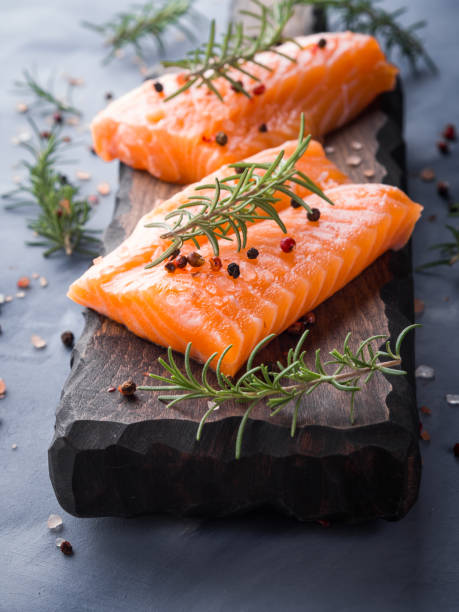 istock Raw salmon on wooden board with herbs 857488892