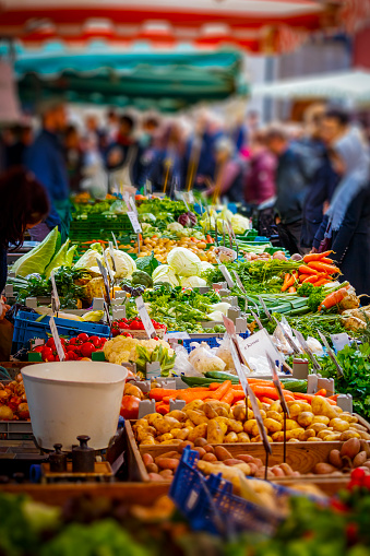 Colorful sales stand with vegetables at the farmers market in Mainz with many people.