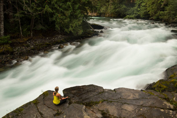 istock Woman practicing yoga alongside a raging river 857505728