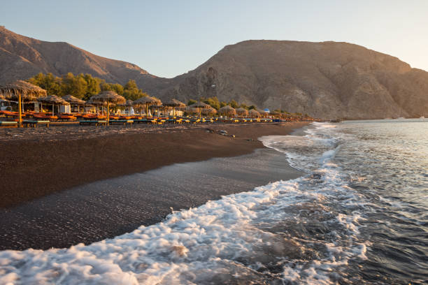 perissa strand bei sonnenaufgang auf der griechischen insel santorini - black sand beach santorini greece stock-fotos und bilder