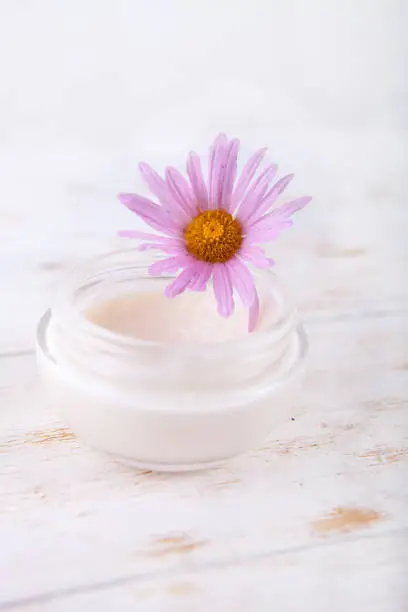 face-cream and flower on a white wooden background. natural organic cosmetic facial.