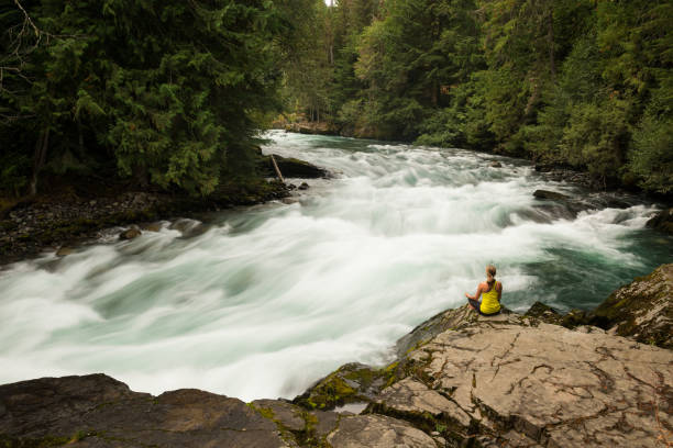 istock Woman practicing yoga alongside a raging river 857510446