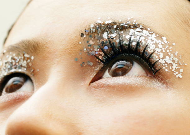 Woman's eyelid with silver color glitters Brown eyes of young woman glitter makeup stock pictures, royalty-free photos & images