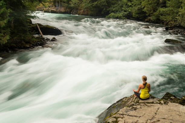 istock Woman practicing yoga alongside a raging river 857510634