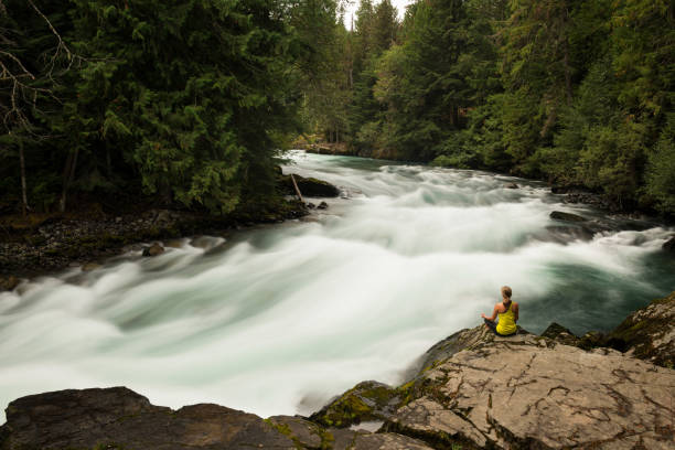 istock Woman practicing yoga alongside a raging river 857510736