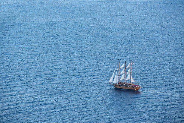 Old wooden boat in deep blue water, Santorini, Greece. View from above.