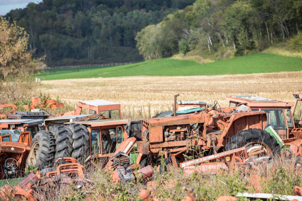 Old rustic tractors sitting on a farm field.