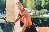 Sports woman splashing with water at the fountain