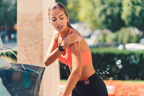 Sports woman splashing with water at the fountain Young woman cooling with water after sports training whites only drinking fountain stock pictures, royalty-free photos & images