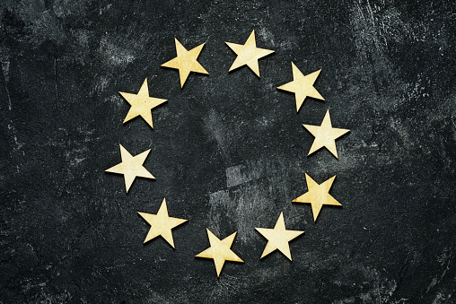 ten wooden stars in a circle on a dark cement background, top view
