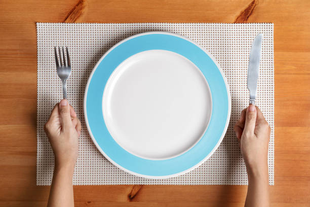 istock Hand hold fork and knife with and empty plate on wood 857545086