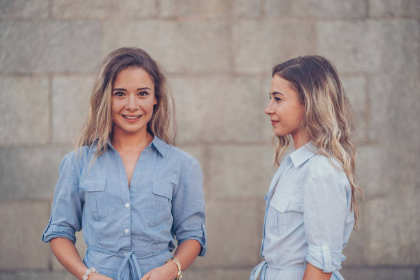 istock Smiling and serious sisters at wall backgorund 857548614