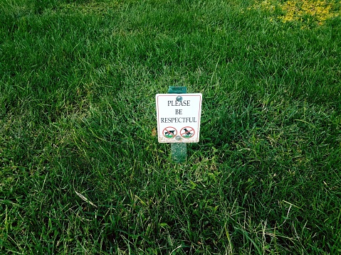 please be respectful sign on the grass with dogs peeing and pooping