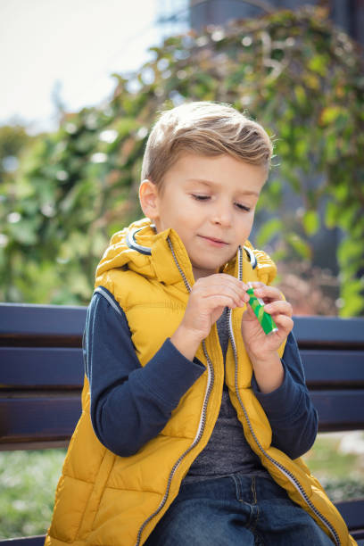 istock Little boy opening chewing gums on a bench. 857562554
