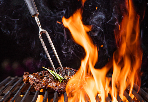 Tasty Beef steaks on the grill with fire flames