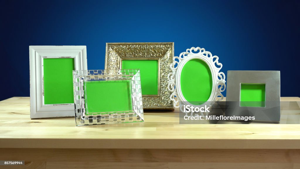 Photo frames in elegant interiors display. Row of photo frames with blank green screens in elegant table interiors display Mantelpiece Stock Photo