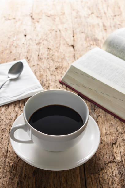 istock Coffee cup and open book on wooden table 857574594