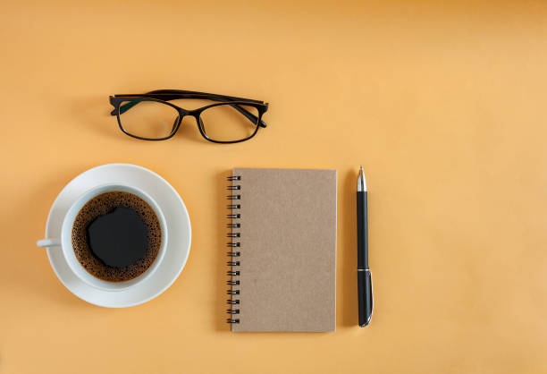 istock Cup of coffee with notebook on yellow background 857574640
