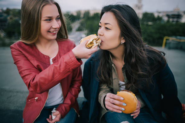 istock Two young girls sharing tasty burger close up 857589400